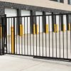 line row of exterior outdoors outside building public storage white garage units behind black metal fence mechanical gate on cement pavement